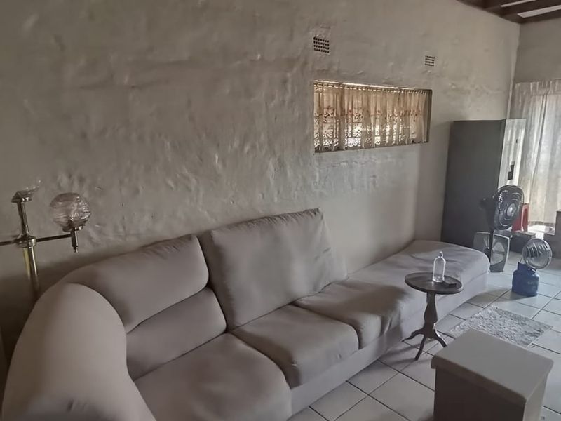 Living room featuring textured plaster walls, exposed timber ceiling beams, and ceramic tiled flooring.