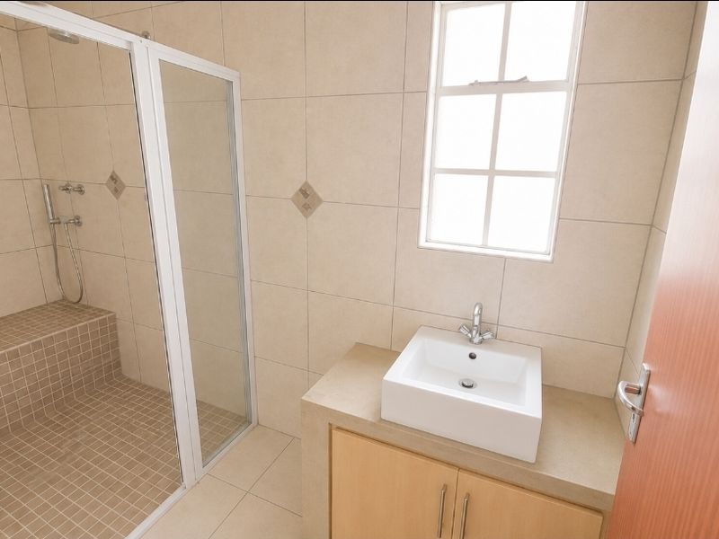 A clean, modern bathroom featuring a walk-in shower with a built-in bench, tiled finishes, and a vanity unit with a vessel sink.