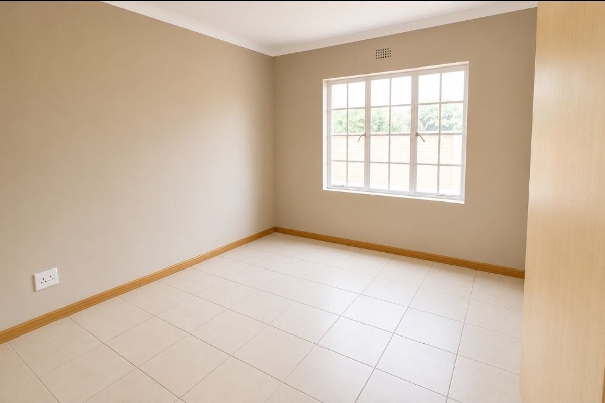 A bright, empty bedroom featuring neutral wall paint, tiled flooring, and a built-in cupboard, offering a clean canvas for personalization.
