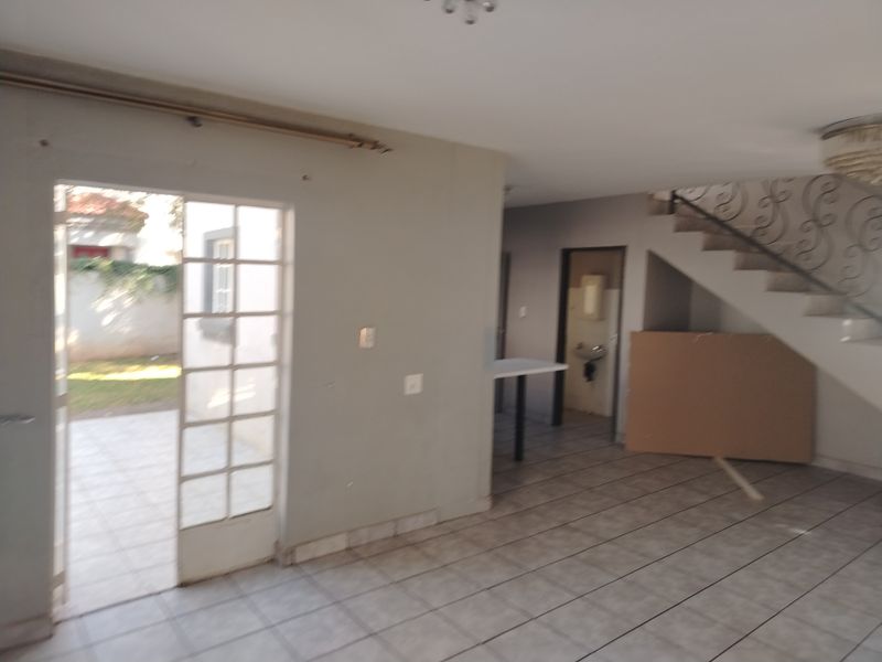 Open plan living area featuring tiled floors, a staircase with decorative wrought iron railing, and direct access to an outdoor patio area.