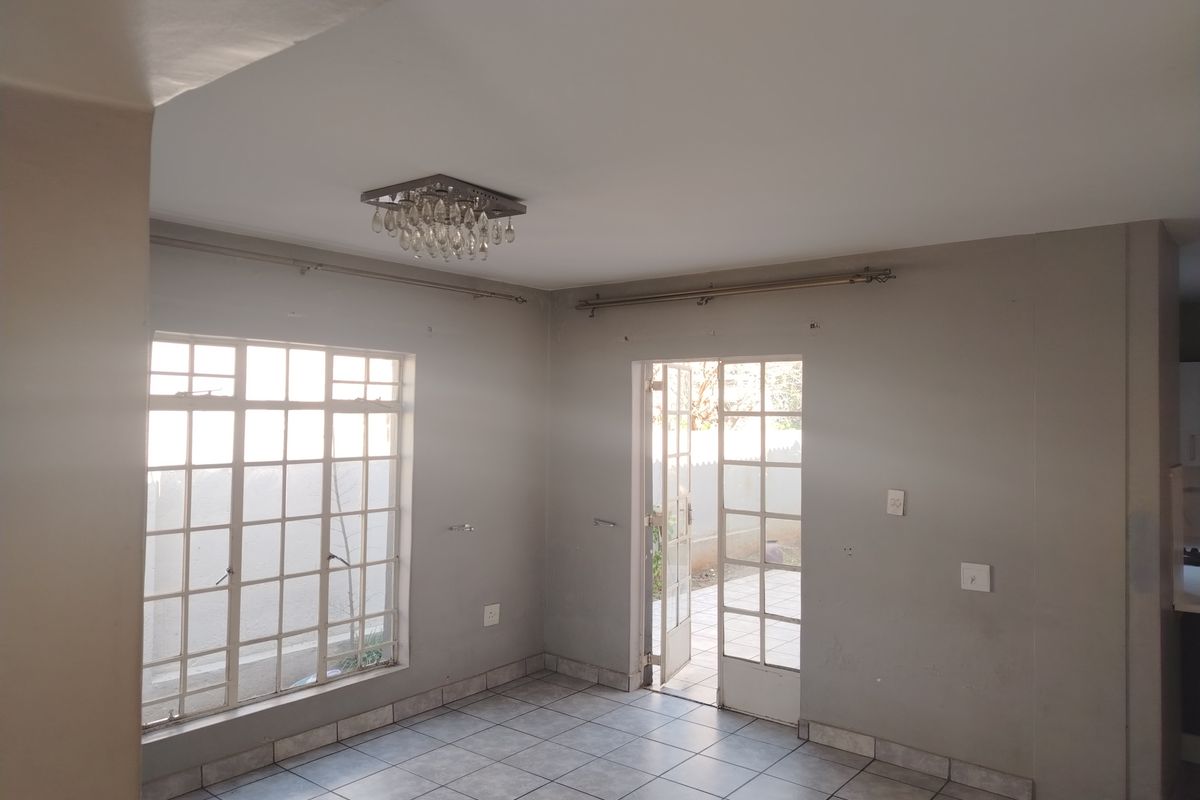 An empty living room featuring tiled flooring, a crystal light fixture, and french doors leading to an outdoor area.