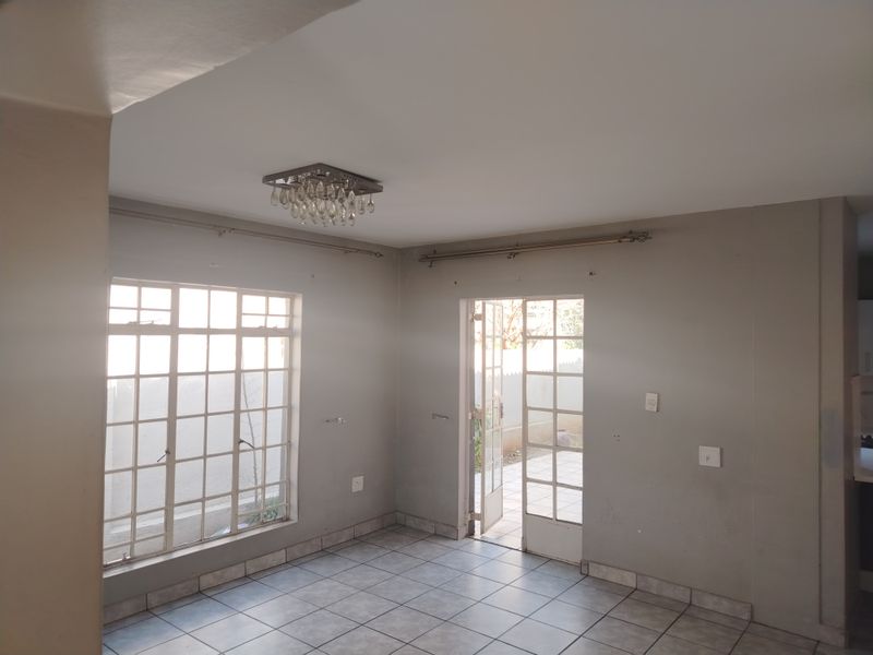 An empty living room featuring tiled flooring, a crystal light fixture, and french doors leading to an outdoor area.