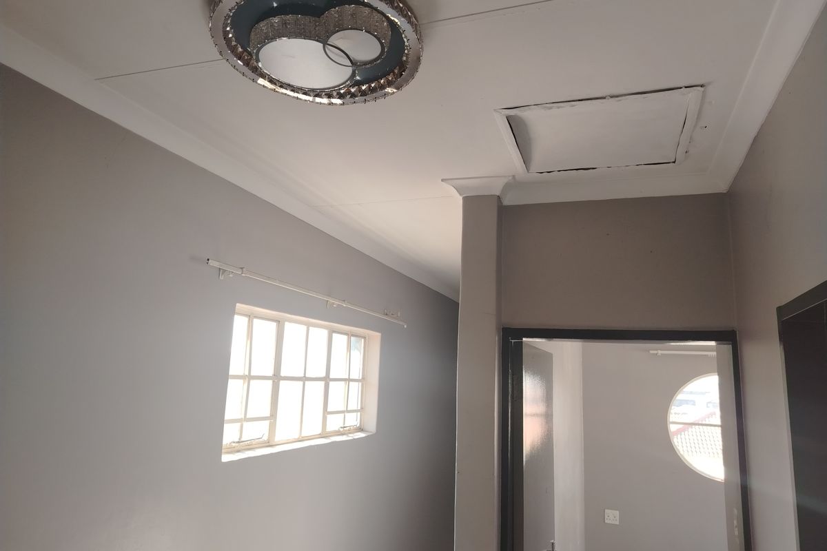 An empty bedroom featuring a decorative ceiling light, loft access hatch, and a combination of standard and circular windows.