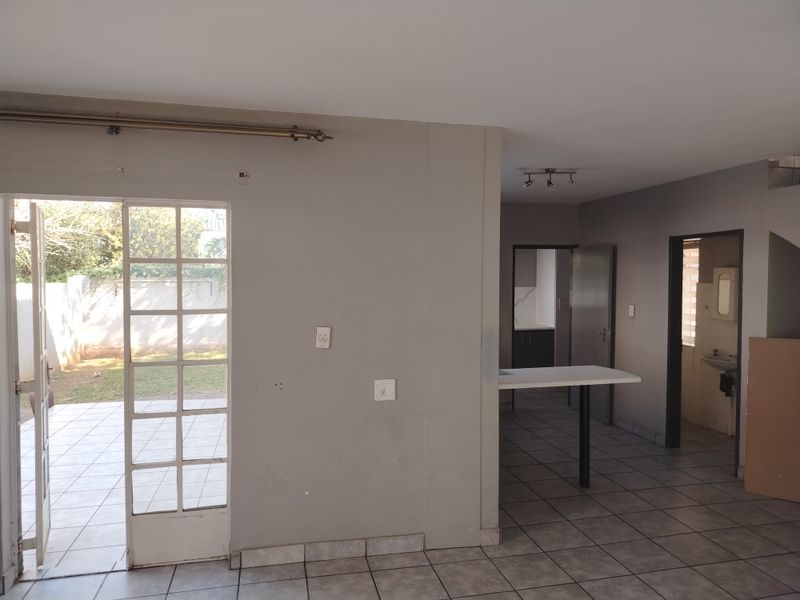 Open plan living area featuring tiled flooring, a breakfast bar, and direct access to the rear patio and garden.