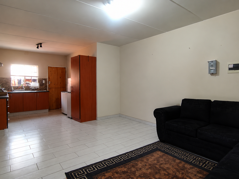 Open-plan living area featuring tiled flooring and a functional kitchen with built-in cabinetry and an extractor fan.