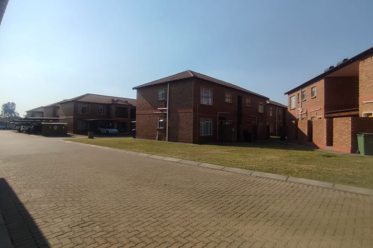 Exterior view of a residential apartment complex featuring face brick buildings, paved driveways, and communal lawn areas.