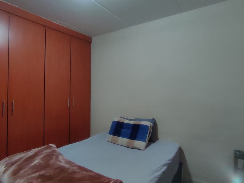A bedroom featuring a large built-in wooden wardrobe with ample storage space.