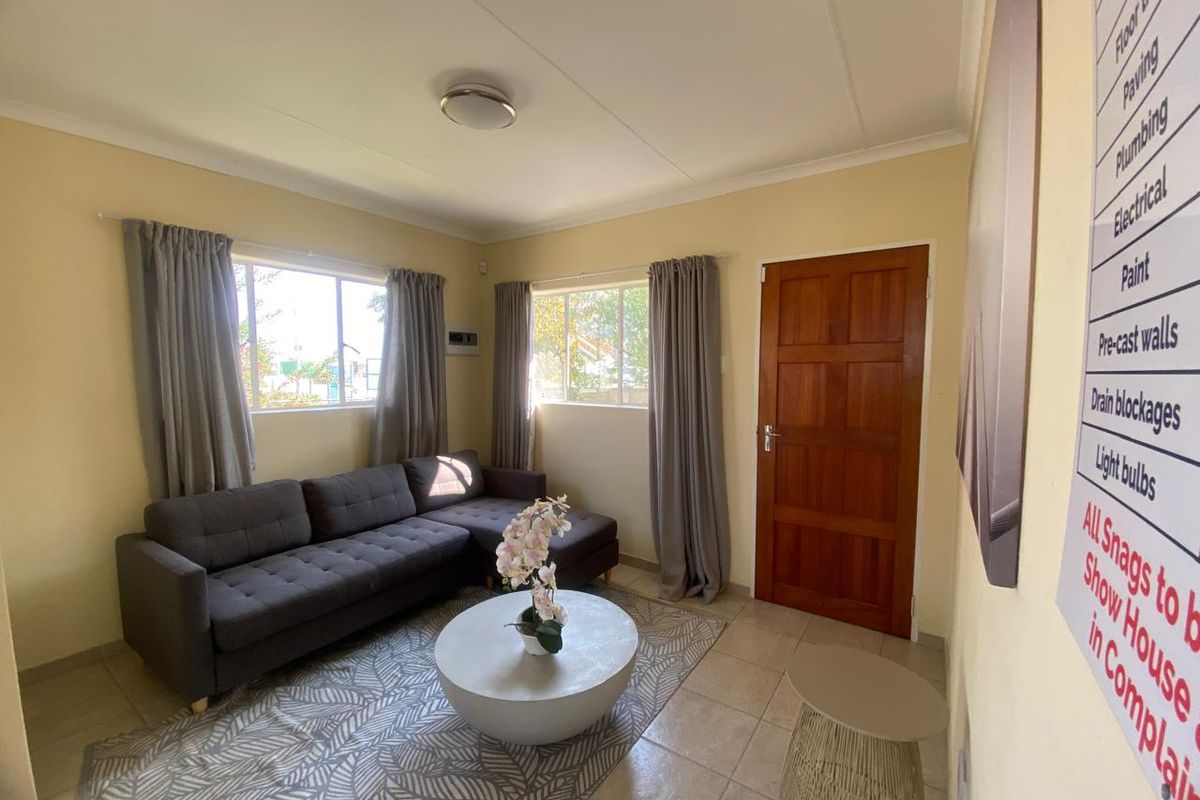 A living room featuring tiled flooring, timber door, and aluminium window frames, providing a functional and well-lit space.