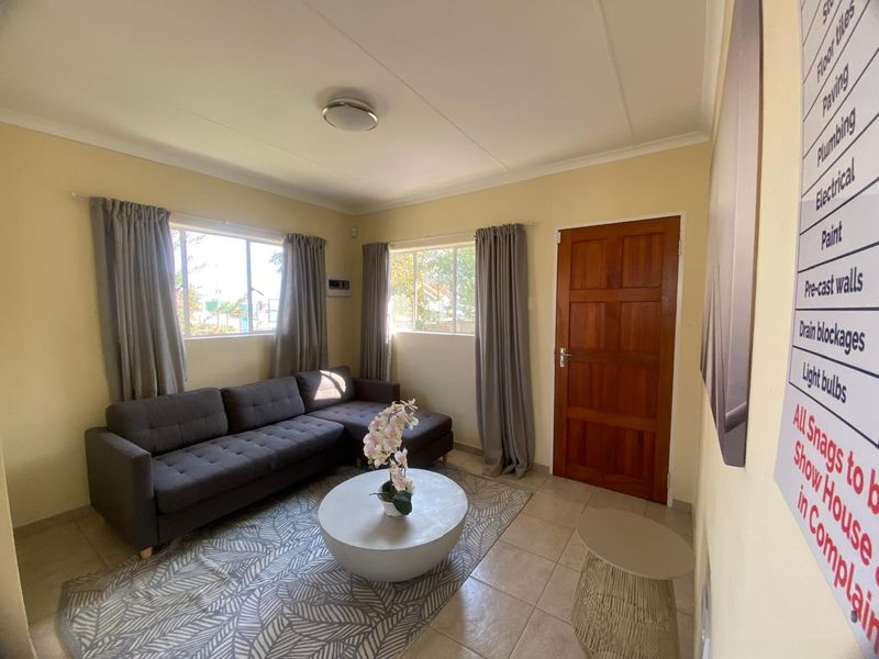A living room featuring tiled flooring, timber door, and aluminium window frames, providing a functional and well-lit space.
