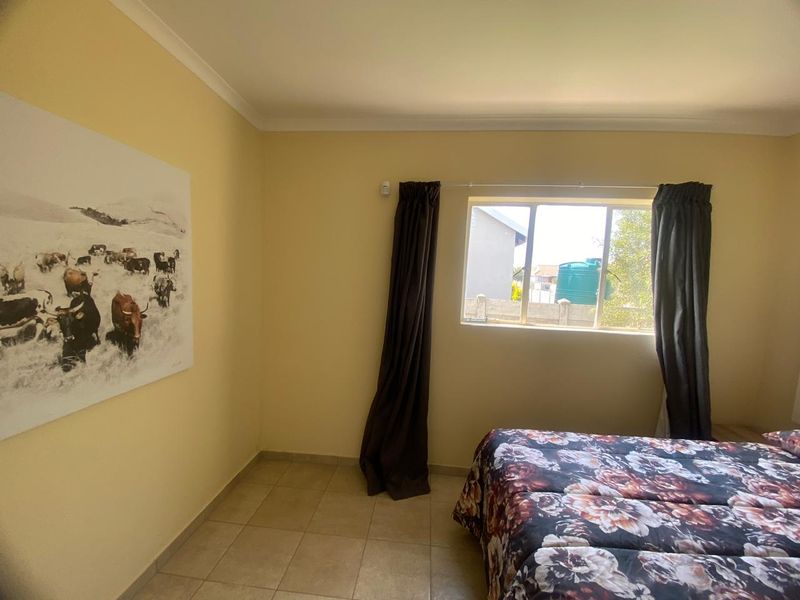 A bedroom featuring neutral wall paint, tiled flooring, and a window providing natural light.