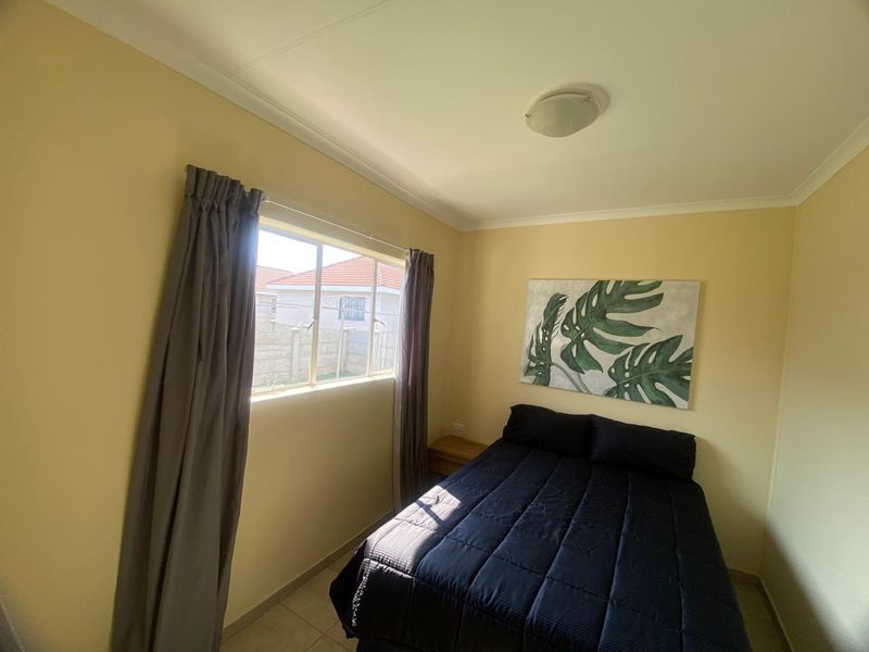 A standard bedroom featuring tiled flooring, neutral wall paint, and a window with curtain tracks.