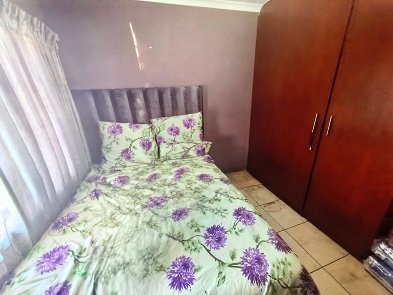 A bedroom featuring tiled flooring and a built-in wooden wardrobe.