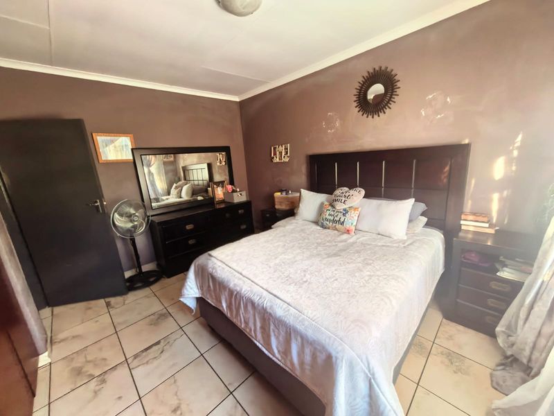 A bedroom featuring tiled flooring and dark-toned walls, providing a functional sleeping space with standard finishes.