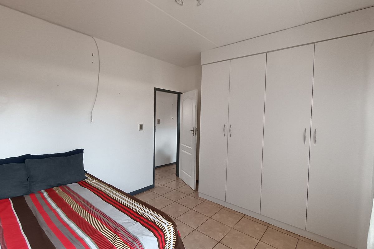 A bedroom featuring tiled flooring and built-in cupboards, providing functional storage space within the apartment.