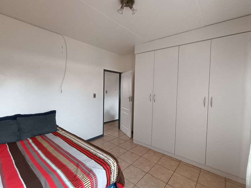 A bedroom featuring tiled flooring and built-in cupboards, providing functional storage space within the apartment.