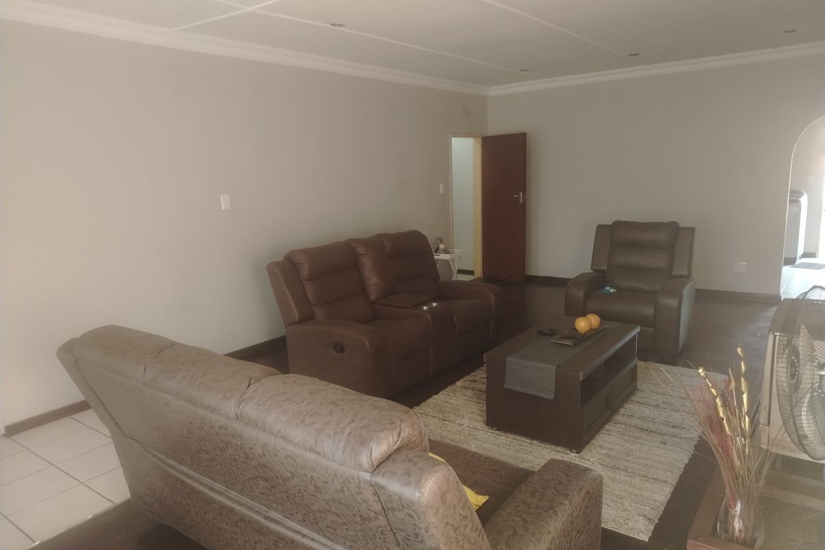 A spacious living room featuring neutral wall tones, recessed ceiling lighting, and tiled flooring, providing a comfortable and versatile area for relaxation.