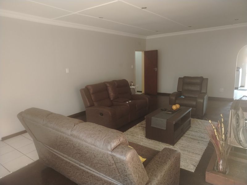A spacious living room featuring neutral wall tones, recessed ceiling lighting, and tiled flooring, providing a comfortable and versatile area for relaxation.
