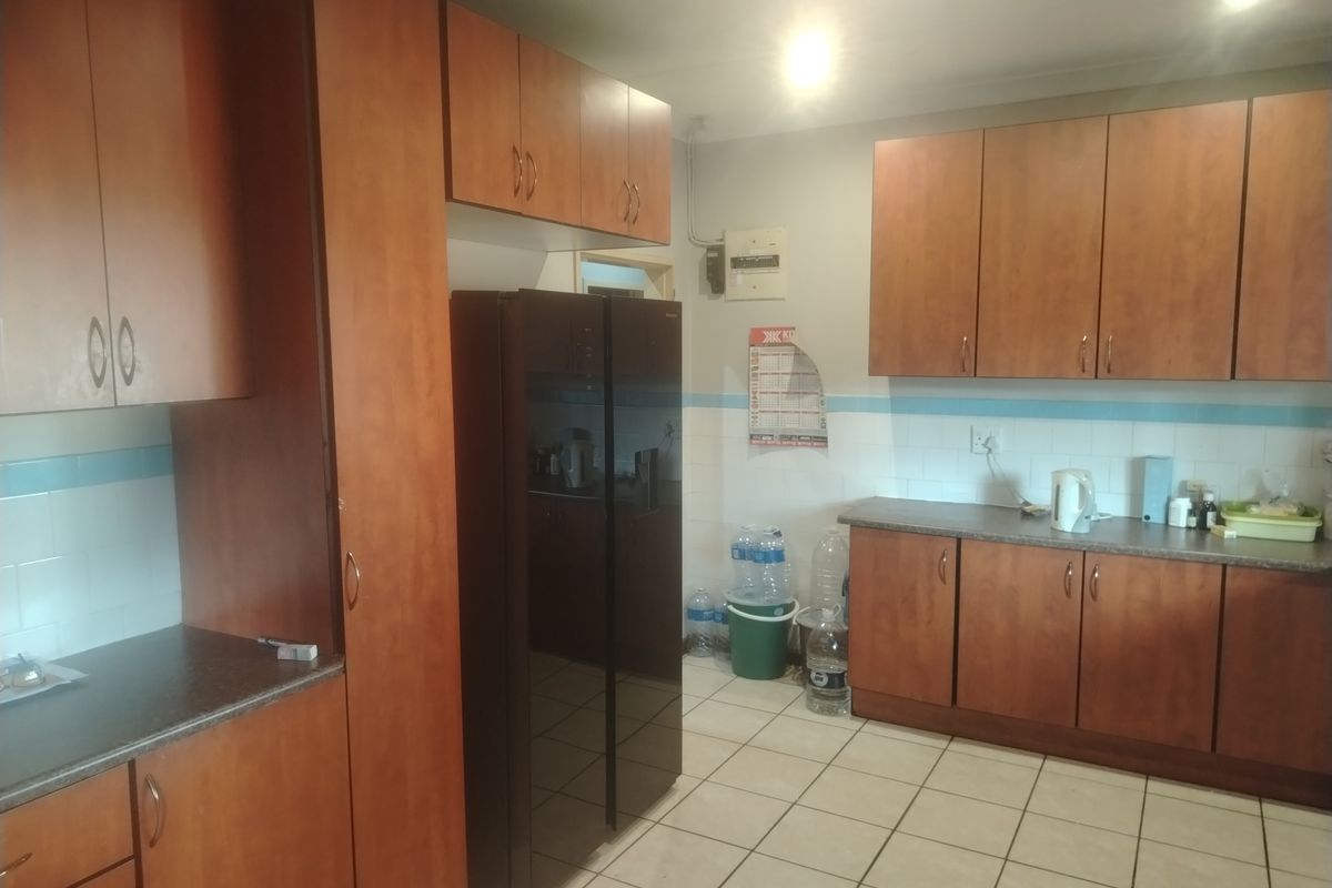 A functional kitchen featuring wood-look laminate cabinetry, tiled backsplash, and ceramic floor tiles, providing ample storage and workspace.