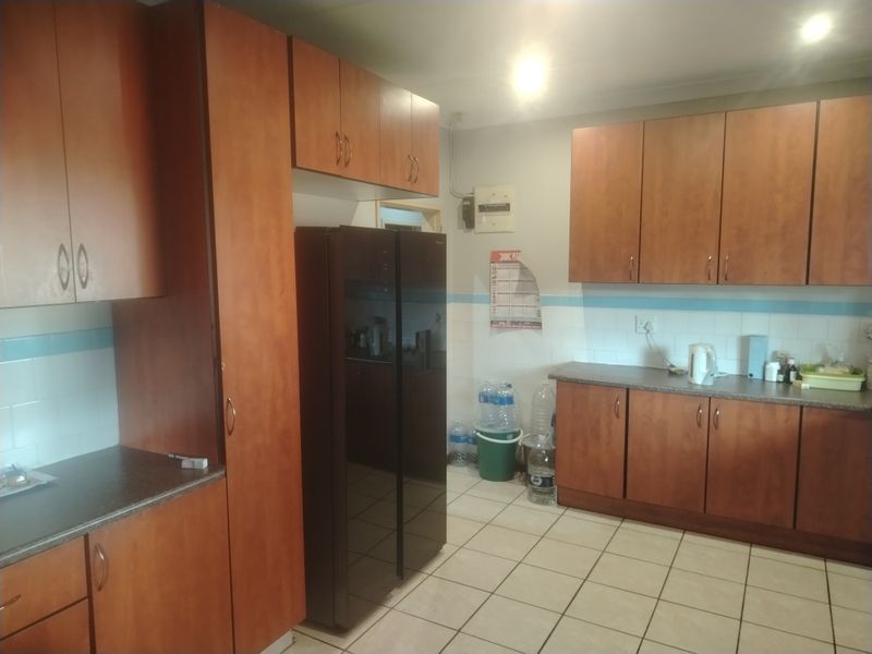 A functional kitchen featuring wood-look laminate cabinetry, tiled backsplash, and ceramic floor tiles, providing ample storage and workspace.