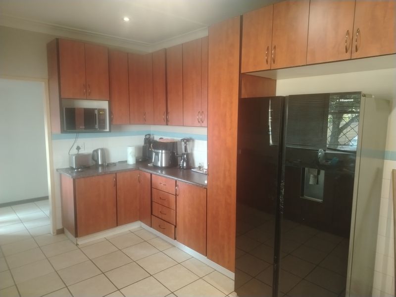 A functional kitchen featuring wood-tone laminate cabinetry, tiled flooring, and a tiled backsplash, providing ample storage and workspace.