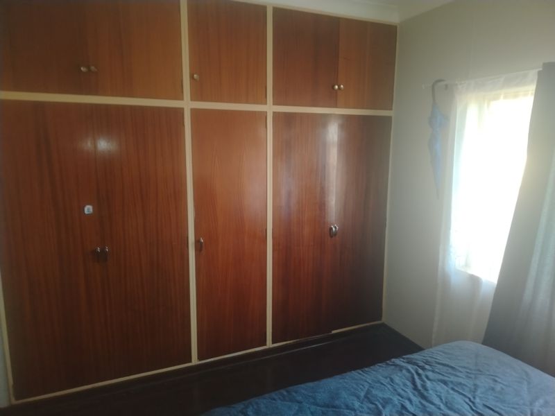 A bedroom featuring floor-to-ceiling built-in wooden cupboards with overhead storage compartments.