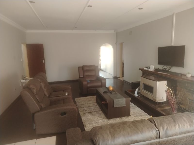 Spacious living room featuring a stone-surround fireplace with a timber mantelpiece, recessed ceiling lighting, and an arched doorway leading to adjacent areas.