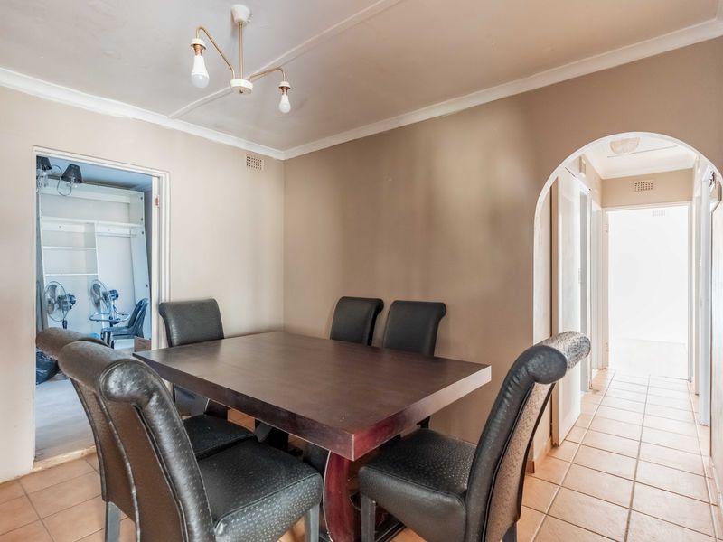 A dining room featuring tiled flooring, a decorative archway, and neutral wall tones, providing a functional space for family meals.