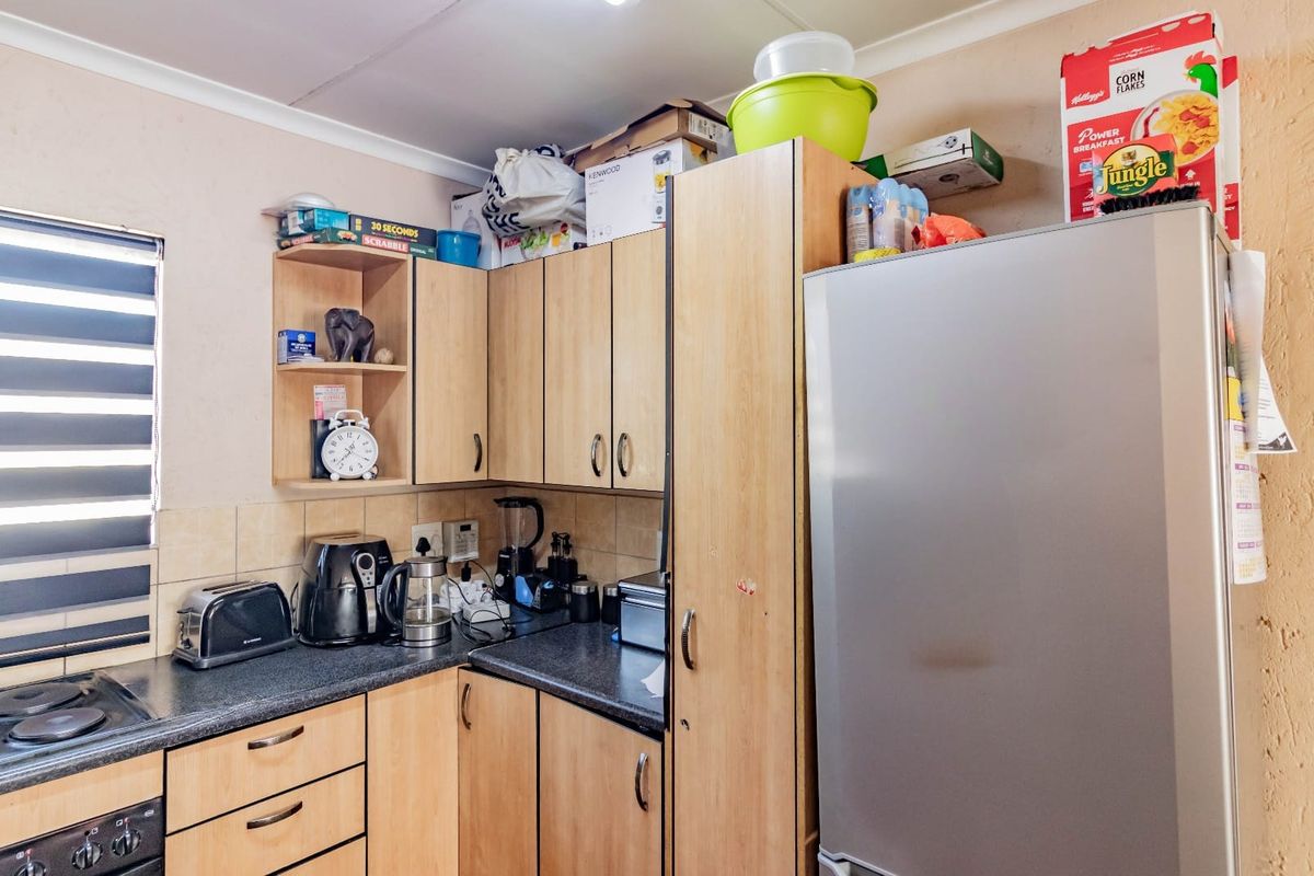 A functional kitchen featuring laminate cabinetry, dark countertops, a built-in hob, and tiled backsplash, offering practical storage and workspace.