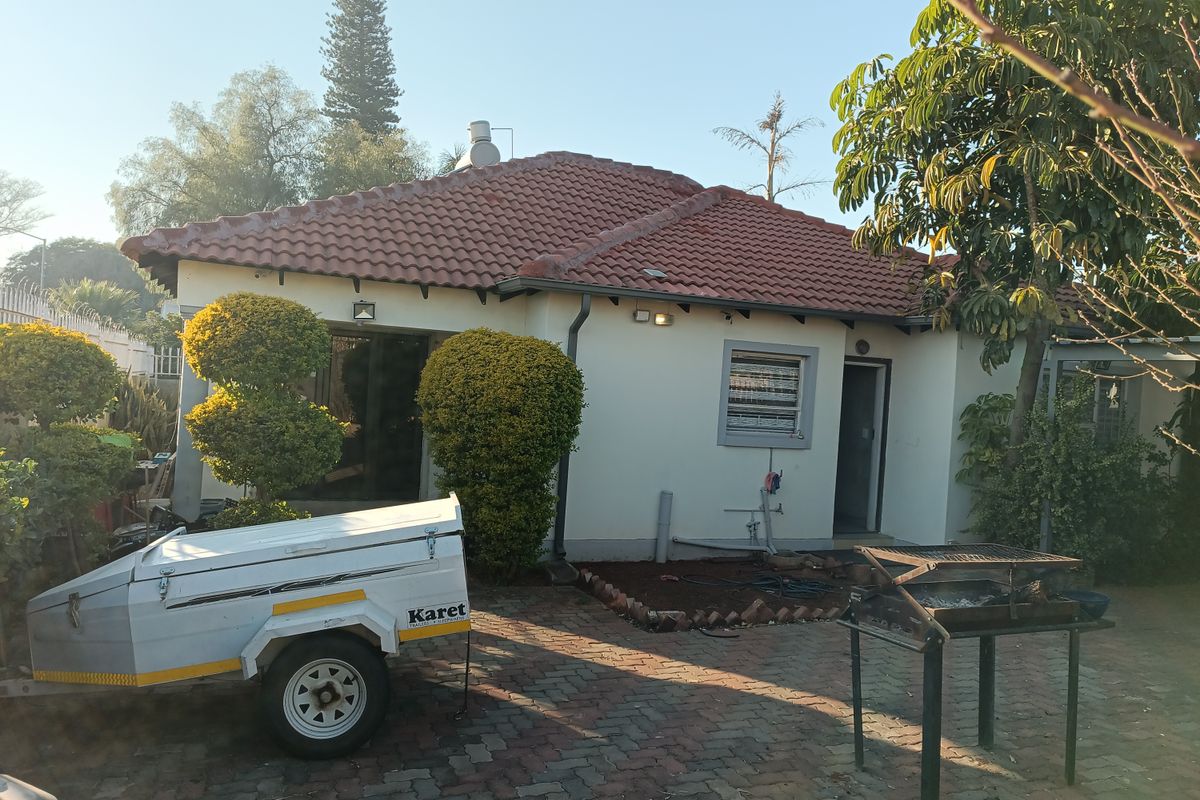 Rear view of the house featuring a tiled roof, paved outdoor area, and exterior wall lighting.