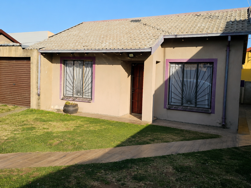 Front elevation of a single-story house featuring a tiled roof, roller shutter garage, and security-fitted windows with a paved walkway leading to the entrance.