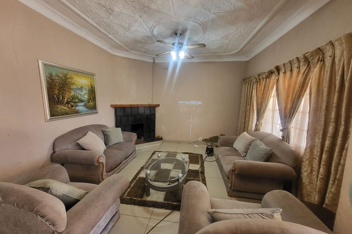 Living room featuring a decorative plaster ceiling, corner fireplace, and tiled flooring. The space requires cosmetic updates to the walls and finishes.