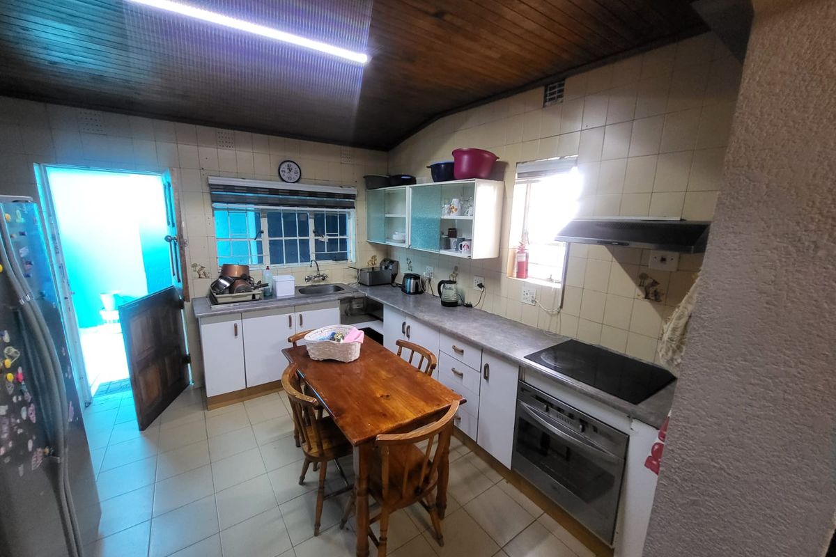 A functional kitchen featuring built-in cabinetry, laminate countertops, an integrated oven and hob, and a timber-clad ceiling with direct access to the exterior.