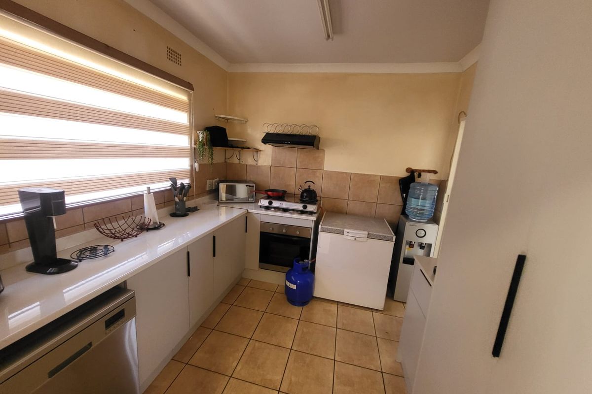 Functional kitchen featuring quartz countertops, built-in oven, gas hob, extractor fan, and tiled splashback with neutral floor tiling.