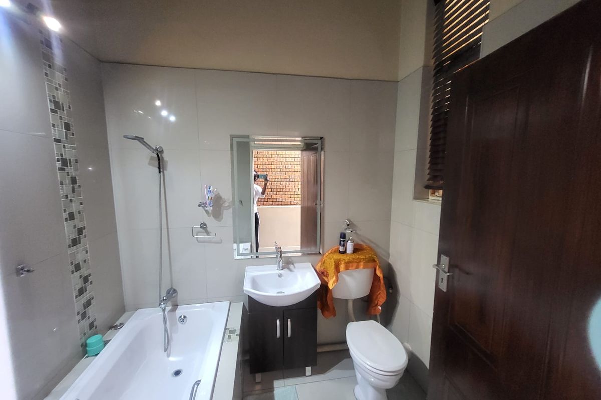 A functional bathroom featuring a bathtub with shower attachment, a vanity unit with basin, and a standard toilet with tiled finishes.