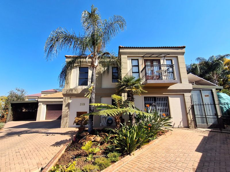Front elevation of a two-story residential property featuring a paved driveway, attached garage, and a private balcony.