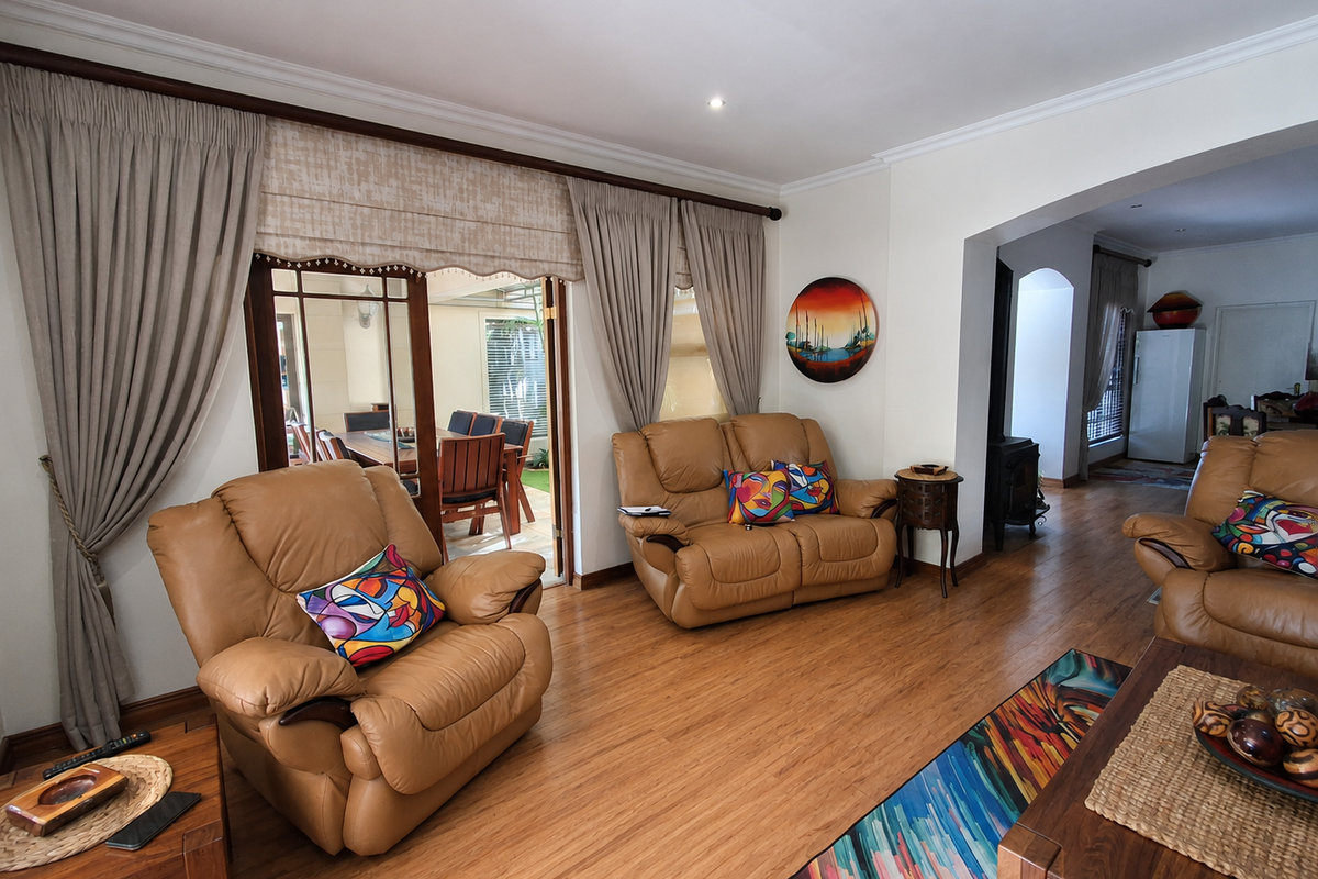 Spacious living room featuring laminate flooring, crown molding, and a wood-burning fireplace, with direct access to an outdoor patio area through sliding glass doors.