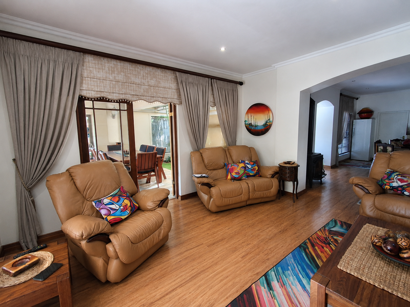 Spacious living room featuring laminate flooring, crown molding, and a wood-burning fireplace, with direct access to an outdoor patio area through sliding glass doors.
