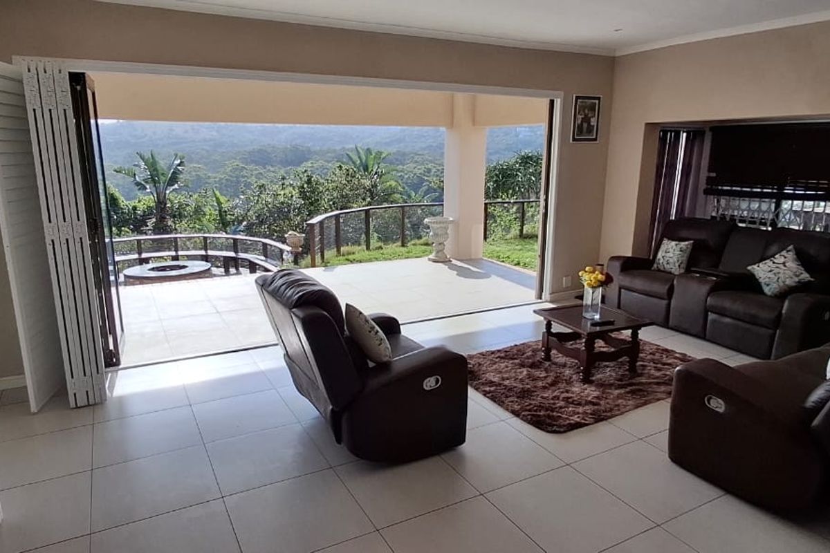 Spacious living room featuring large bi-fold doors that open onto a covered patio with scenic views, creating a seamless indoor-outdoor flow.