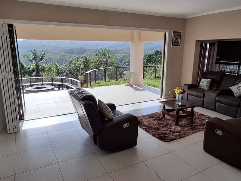 Spacious living room featuring large bi-fold doors that open onto a covered patio with scenic views, creating a seamless indoor-outdoor flow.