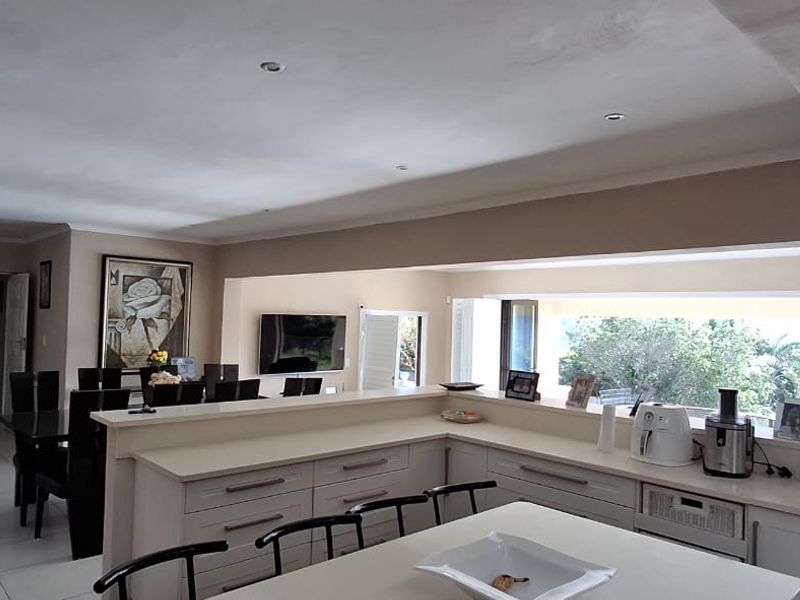 Spacious open-plan kitchen and dining area featuring a central island, ample built-in cabinetry, and neutral finishes with views to the exterior.