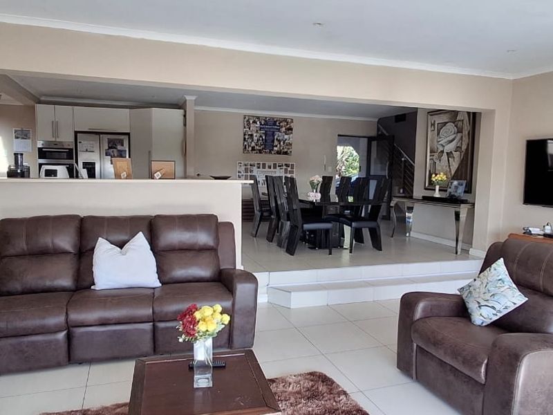 Spacious open-plan living and dining area featuring tiled floors, a raised dining platform, and a functional kitchen with built-in appliances.