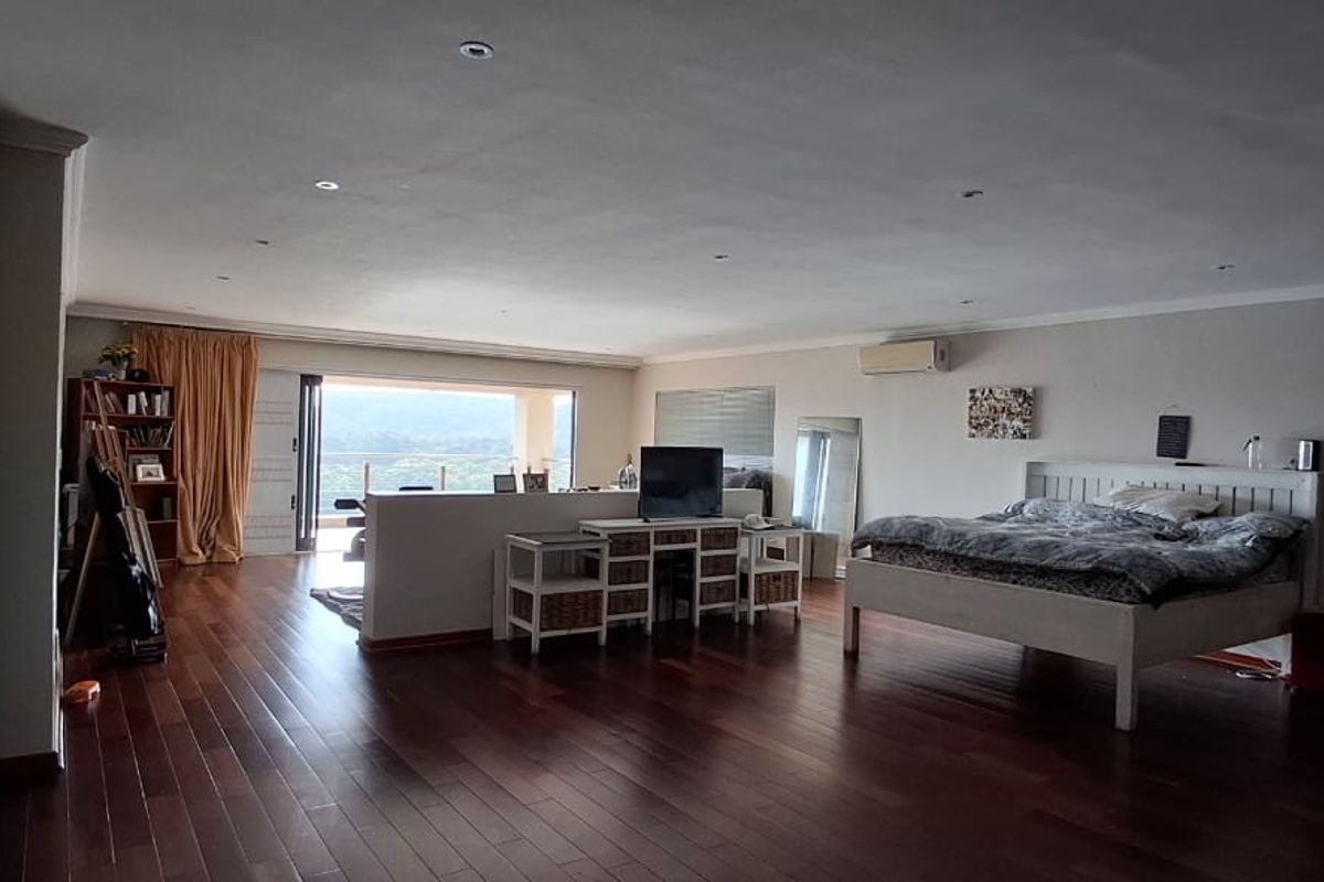 Spacious bedroom featuring rich hardwood flooring, recessed lighting, built-in storage, and direct access to a balcony with scenic views.
