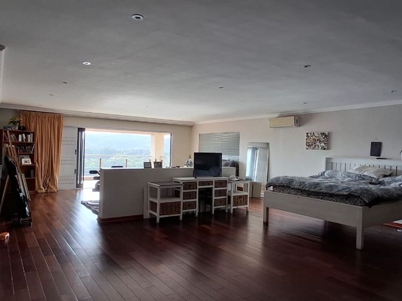 Spacious bedroom featuring rich hardwood flooring, recessed lighting, built-in storage, and direct access to a balcony with scenic views.