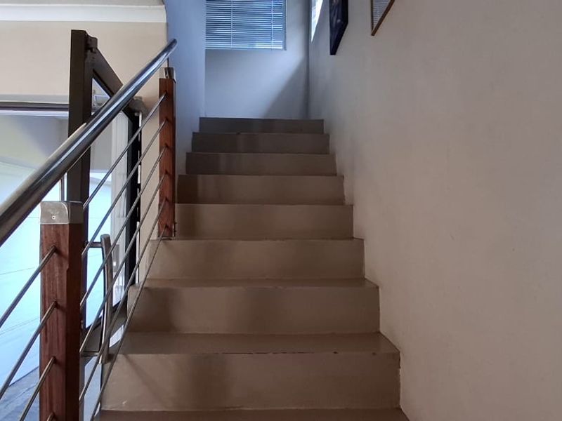 A functional staircase featuring a modern stainless steel and wood balustrade, leading to an upper level with natural light from a window.