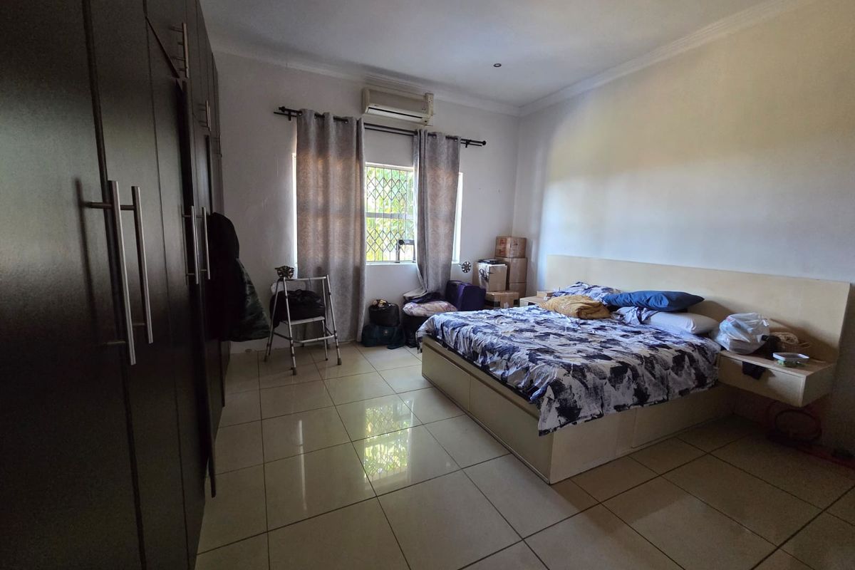 Spacious bedroom featuring large built-in cupboards, tiled flooring, and an integrated air conditioning unit for climate control.