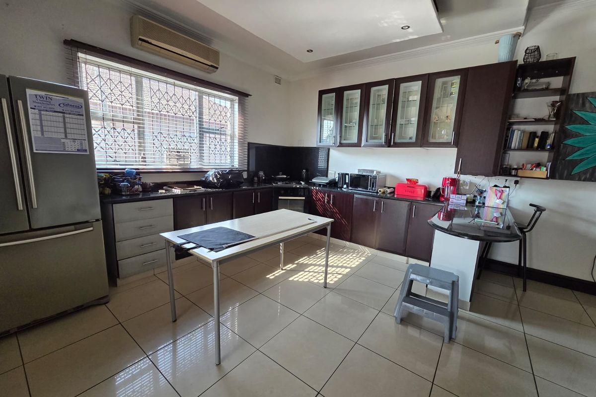 A functional kitchen featuring dark wood cabinetry, granite countertops, tiled flooring, and a breakfast bar, offering ample storage and workspace.