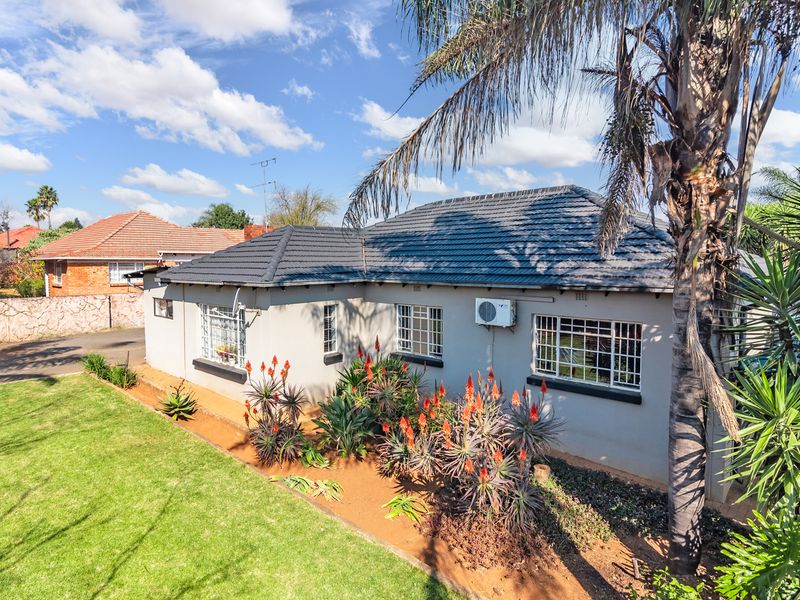 A well-maintained rear exterior view of the house featuring a tiled roof, security-barred windows, and a landscaped garden area.
