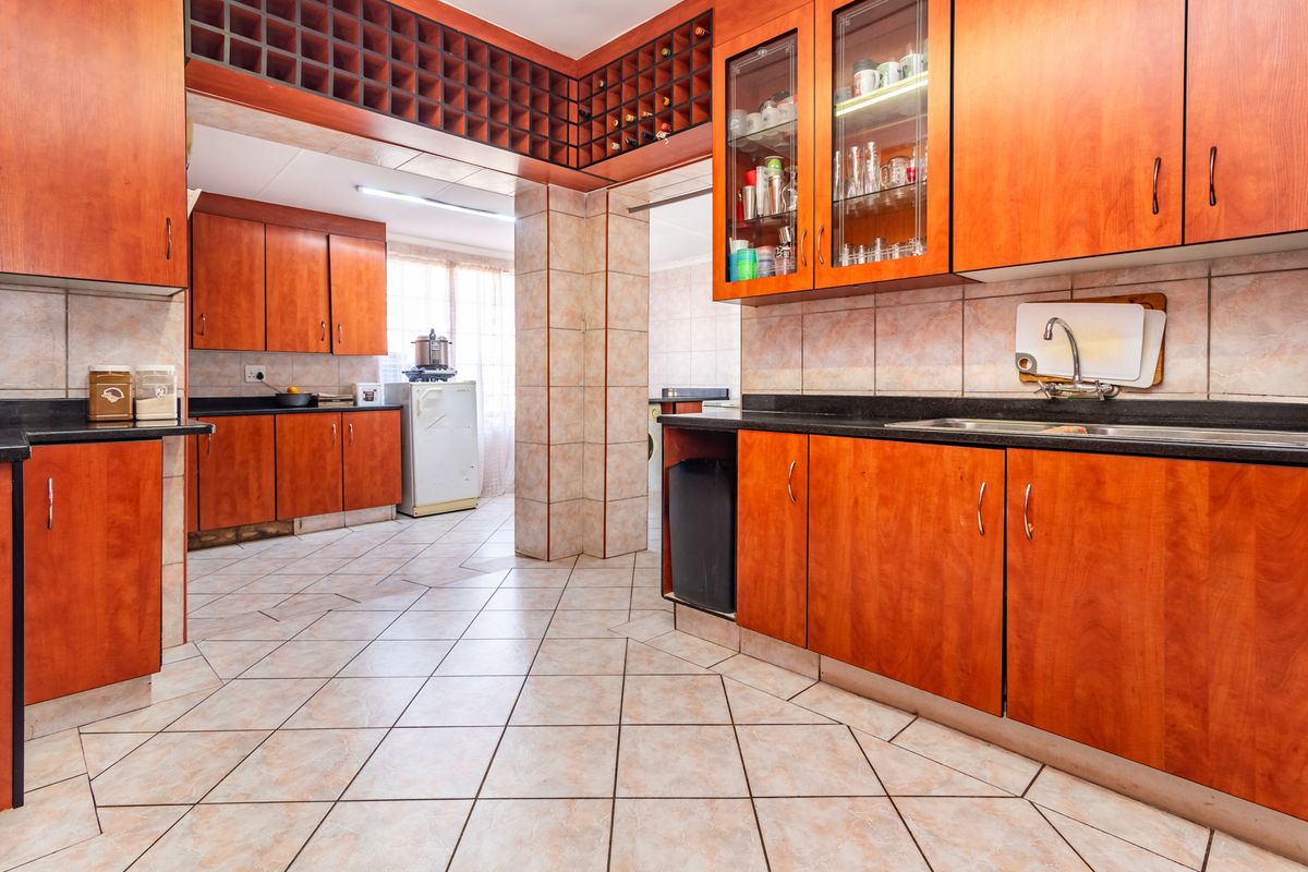Spacious kitchen featuring extensive wooden cabinetry, granite countertops, integrated wine storage, and tiled flooring with a functional layout.
