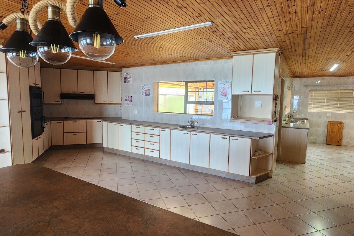 Spacious kitchen featuring extensive built-in cabinetry, double wall oven, tiled flooring, and a distinctive timber ceiling, offering a functional layout with ample storage space.