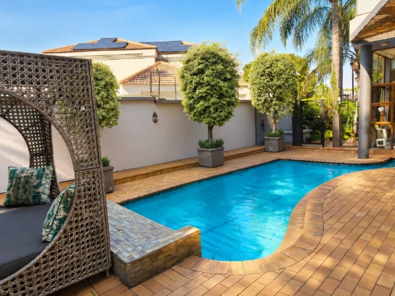 A well-maintained outdoor pool area featuring brick paving, a tiled pool edge, and a secure boundary wall, perfect for relaxation and outdoor entertainment.